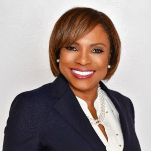 Abbey Ajayi, Broward County Tax Collector, smiling in a professional headshot wearing a navy blazer, white blouse, and pearl necklace.