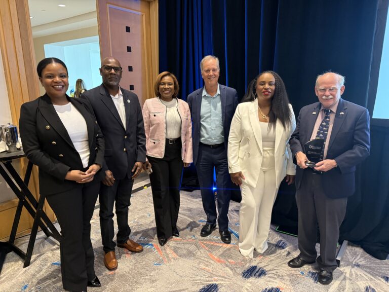 Broward County Tax Collector Abbey Ajayi, wearing a pink jacket, poses with business and community leaders at the Greater Hollywood Chamber of Commerce awards ceremony.