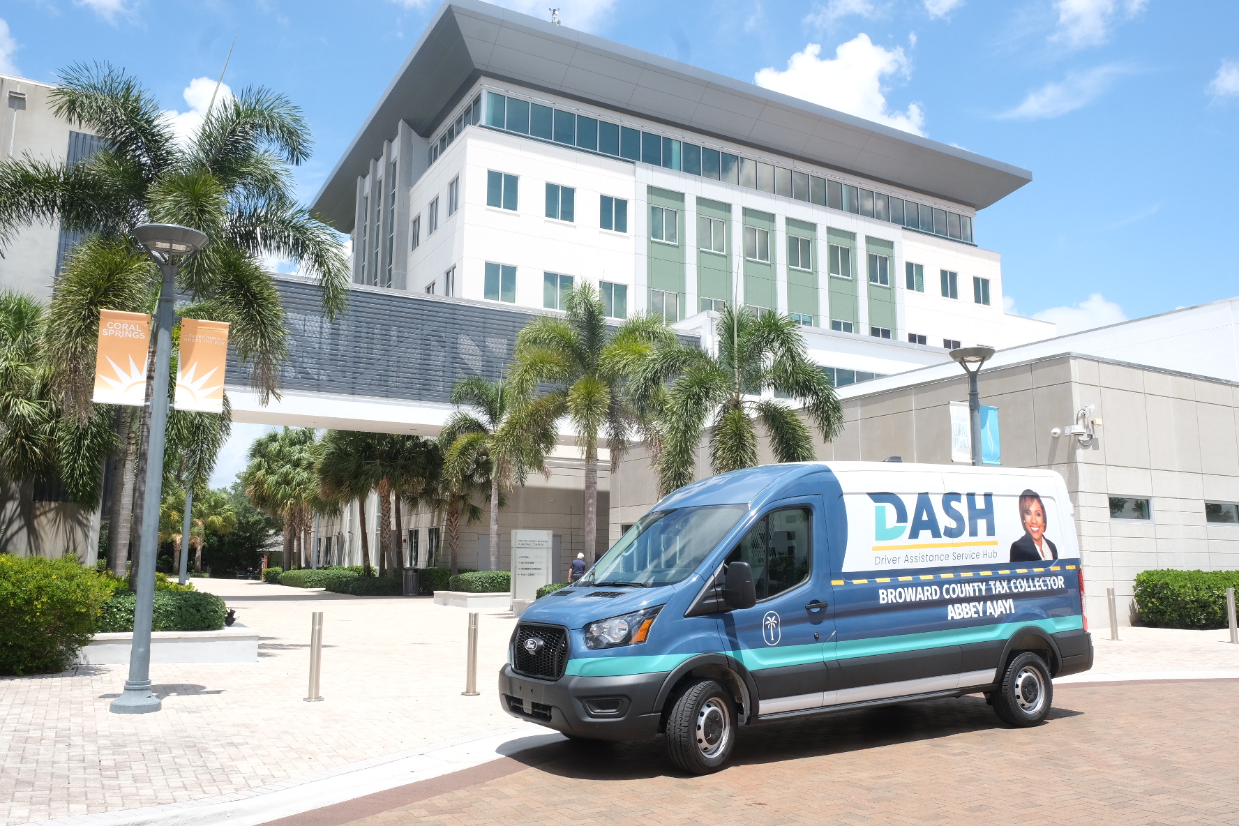 Broward County Tax Collector DASH Driver Assistance Service Hub mobile van parked outside a Coral Springs government building in Florida.